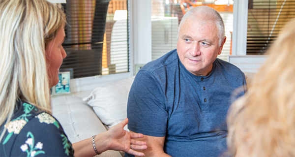 A person listening attentively to a person speaking, sitting on a sofa.
