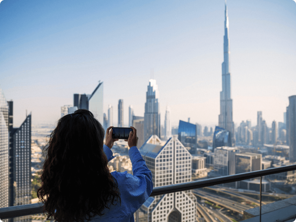 Image Description: A traveler taking a photo of the Burj Khalifa from a high-rise balcony in Dubai
